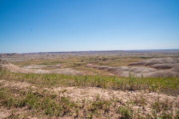Open grassland with distant Badlands rock formations.
