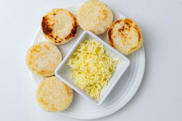 Traditional Colombian and Venezuelan arepas, homemade white corn cakes served with shredded cheese for breakfast or as a snack, a typical gluten-free dish from South America, on a white background
