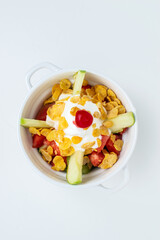 Colombian fruit salad (Salpicón or Copa de Frutas) with fresh apple, cherry, corn flakes, and yogurt cream, a healthy and refreshing dessert or breakfast bowl isolated on a white background.