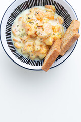 Gourmet creamy garlic shrimp or shrimp scampi (Camarones al Ajillo) in a buttery herb sauce, served as an appetizer or main course with toasted bread in a stylish bowl, isolated on a white background.