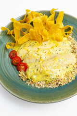 Gourmet baked fish fillets in a creamy lemon herb sauce with a breadcrumb crust, served with crispy plantain chips (platanitos) and cherry tomatoes, a healthy main course dish on a white background.