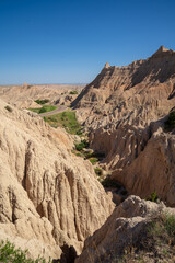 Eroded rock formations and green trees in Badlands National Park, South Dakota