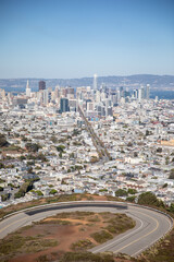 Aerial view of San Francisco with buildings, roads, and skyline under a clear blue sky.