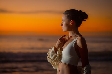 Profile portraif of a boho style woman gazing at ocean sunset