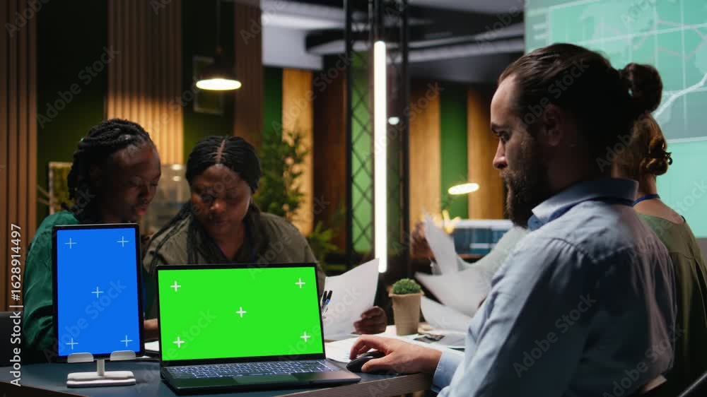 Poster multiethnic team of experts in a meeting with a chroma key laptop, analyzing insights and establishi
