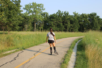 Obraz premium Woman with long hair on roller blades on the North Branch Trail at Miami Woods in Morton Grove, Illinois