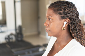 Woman listening music with wireless earbuds in gym