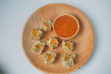 Steamed Dumplings with Spicy Sauce on Wooden Plate
