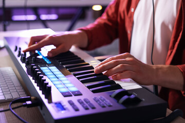 Man working with MIDI keyboard at table indoors, closeup