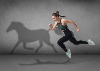 Athletic young woman running. Her shadow in form of horse on brick wall. Sports poster