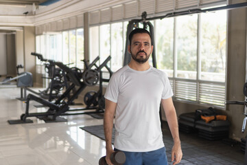 Determined man holding dumbbell, ready for workout in gym