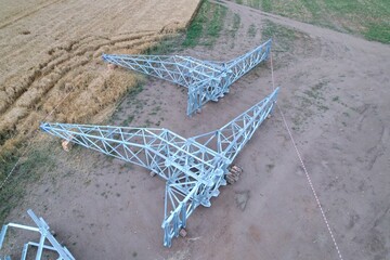High-voltage pylon disassembled on ground with concrete bases before helicopter installation