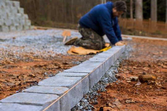 Construction worker carefully places cinder blocks on gravel to create pathway