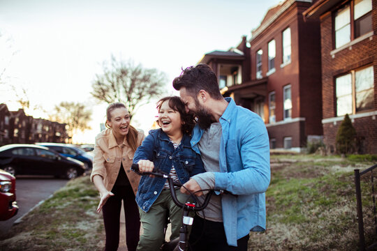 Parents teaching young son how to ride a bike outside