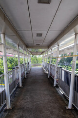 Typical pedestrian overpass walkway in Thailand with urban surroundings, railings, and concrete path under daylight. Common city infrastructure for safe street crossing.