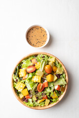 Top view of healthy vegetable salad in wooden bowl with Japanese sesame dressing on white background