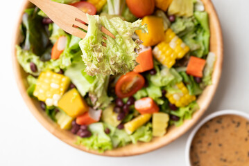 Top view of healthy vegetable salad in wooden bowl eating with Japanese sesame dressing 
