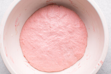 Overhead view of strawberry sourdough proofing in a bowl, top view of pink bread dough
