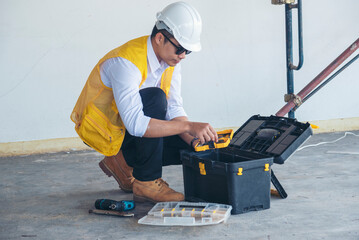 Portrait Civil Construction engineer man holding blueprint file folder working on site wear hard...