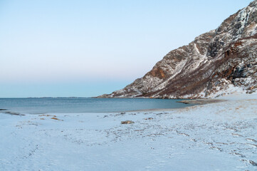 Landscape shot highlighting the rugged mountains and snow-covered beaches of arctic norway during a...