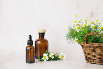 Brown glass bottles arranged artfully alongside a basket of chamomile flowers. Natural aesthetic ideal for herbal remedies. Alternative medicine, healthy and well-being theme concept