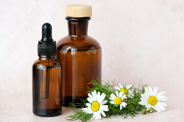 Natural aesthetic ideal for herbal remedies. Brown glass bottles arranged artfully alongside a of chamomile flowers. Alternative medicine, healthy and well-being concept