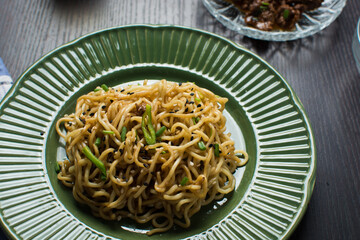 Overhead view of sesame noodles on a green plate, top view of fried ramen noodles with sesame