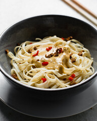 top view of creamy peanut sauce noodles, overhead view of peanut butter noodles in a bowl with red peppers