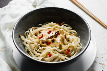 top view of creamy peanut sauce noodles, overhead view of peanut butter noodles in a bowl with red peppers
