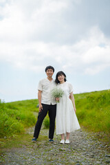 A thirtysomething couple stands together on a mountain trail, the woman with midlength hair in a...
