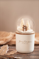 Christmas snow globe featuring gingerbread house and pine trees in neutral colors