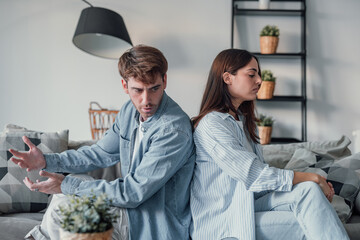 Beautiful lady is depressed, sitting on the couch talking to man, having a dispute with husband or...