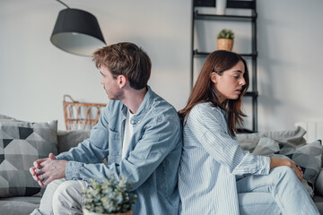 Beautiful lady is depressed, sitting on the couch talking to man, having a dispute with husband or...
