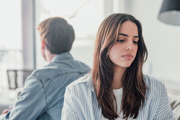 Beautiful lady is depressed, sitting on the couch talking to man, having a dispute with husband or girlfriend, looking desperate and hopeless, having unresolved problem or question