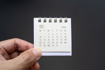 Hand Holding Desk Calendar for OCTOBER 2025 background. Calendar concept with 2025 OCT calendar on...