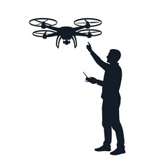 Silhouette of a man operating a drone with a remote control and pointing upwards in the air outdoors