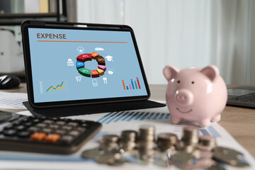 Expense analysis concept shown through colorful financial charts on a tablet screen as a person manages personal budgeting with coins, piggy bank, and calculator in a home office setup.