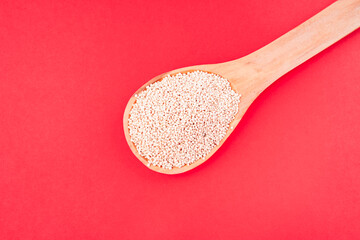 Quinoa in an ancient ceramic bowl with a wooden spoon on a colorful fabric with a black background