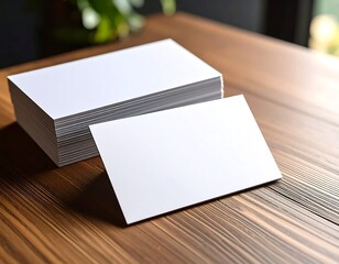A stack of blank business cards rests on a wood table, with a single card angled in front