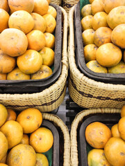 Close-up shot of a pile of Medan oranges in a grocery store. The yellow-skinned tropical fruit displayed for sale in a supermarket. The tropical fruit has a sour and sweet taste. Advertisement Space.