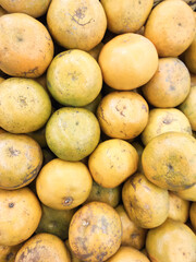 Close-up shot of a pile of Medan oranges in a grocery store. The yellow-skinned tropical fruit displayed for sale in a supermarket. The tropical fruit has a sour and sweet taste. Advertisement Space.