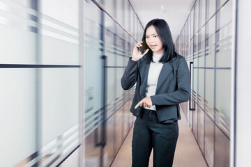 Frustrated businesswoman talking on a mobile phone in an office hallway