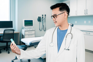 Doctor in a lab coat and stethoscope holding a bottle of medicine