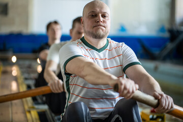 Dedicated powerful athletic rowers in perfect synchronization stroking puddling on indoor rowing...