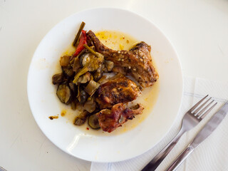 On plate is piece of dietary rabbit meat on bone, cooked in its own juice with baked vegetables.
