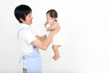 白背景の前で赤とゃんを抱き上げる若い男性。コピースペースあり