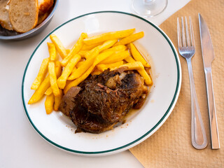 Appetizing baked pork cheeks served with vegetable garnish of fried potatoes. Typical Spanish cuisine