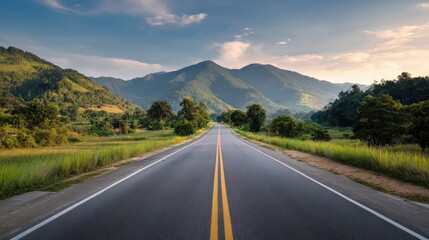 Open Road to Serenity: A long, winding road stretches toward majestic mountains beneath a clear, blue sky, promising a journey of tranquility and boundless exploration.