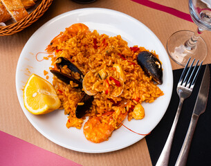 Paella made of rice and different seafood served in plate with other table appointments