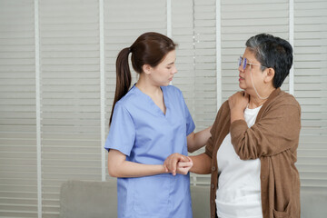 Senior asian woman follows physical therapy instructions while stretching arm across chest under...